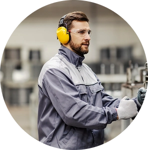 Productiemedewerker met gehoorbescherming en veiligheidsbril aan het werk in een industriële omgeving.